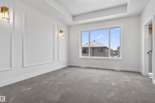 This room features a high tray ceiling, a large window providing natural light, and grey carpet - 11 Redbud Way, St. Albert, AB - Indoor Photo Showing Other Room