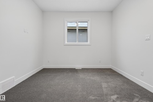 This room features light-colored walls, a window with white trim, and dark gray carpeting - 11 Redbud Way, St. Albert, AB - Indoor Photo Showing Other Room