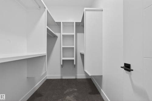 Walk-in closet featuring white built-in shelving, hanging rods, and dark carpeting - 11 Redbud Way, St. Albert, AB - Indoor With Storage