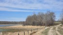 Expansive undeveloped land featuring a dirt track, a wire fence, mature trees, a natural body of water, and broad open space - 11 Twin Lakes Drive, Rural Lamont County, AB 