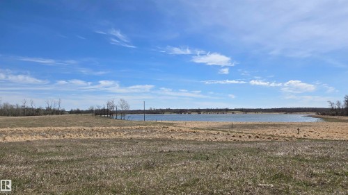 Expansive open land with water frontage, featuring a large body of water, natural terrain, and distant tree lines - 11 Twin Lakes Drive, Rural Lamont County, AB 