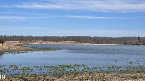 Waterfront property featuring a broad expanse of water, surrounding dry grassland, and a distant tree line - 11 Twin Lakes Drive, Rural Lamont County, AB 