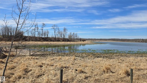 Expansive natural landscape featuring a prominent body of water, surrounded by dry grasses and distant deciduous trees - 11 Twin Lakes Drive, Rural Lamont County, AB 