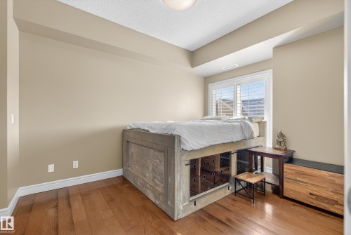 This room features hardwood flooring, a window with horizontal blinds, and neutral-toned walls - 307 9750 94 Street, Edmonton, AB - Indoor Photo Showing Other Room