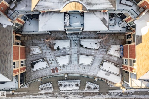 Aerial view of the property's exterior, showcasing the central courtyard with planter beds and a paved walkway - 307 9750 94 Street, Edmonton, AB - 