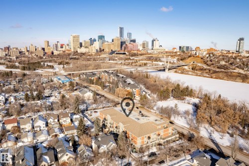 Aerial view showcasing the property's location within a residential area, with a cityscape visible in the distance across a river - 307 9750 94 Street, Edmonton, AB - Outdoor With View