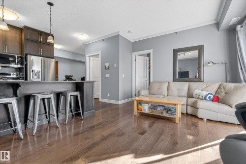 Living area featuring hardwood flooring, light grey walls, and white crown molding - 307 9750 94 Street, Edmonton, AB - Indoor