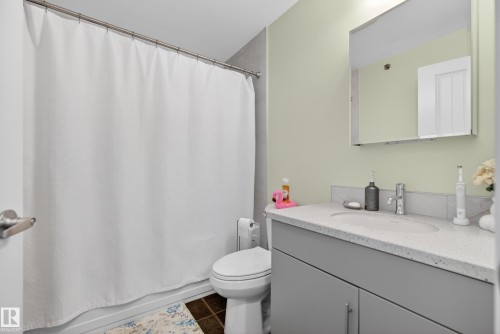 This bathroom features a contemporary vanity with a spacious countertop, a wall-mounted mirror, and a white shower curtain - 307 9750 94 Street, Edmonton, AB - Indoor Photo Showing Bathroom