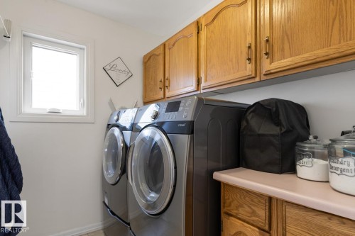Main Floor Laundry Room With Convenient Cupboards And Counter Space Plus A Laundry Shute From The Upper Level Bathroom. - 12824 157 Avenue, Edmonton, AB - Indoor Photo Showing Laundry Room
