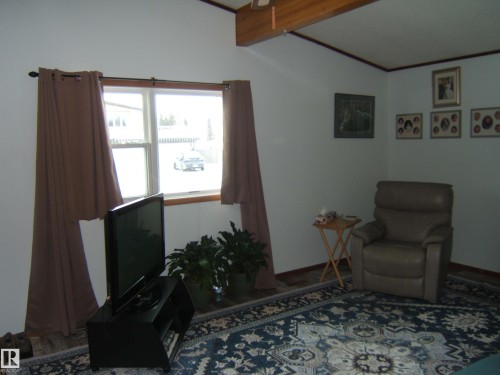 Living area featuring white walls, a window with a wood sill, and a dark patterned rug - 4702 52 Avenue, Two Hills, AB - Indoor