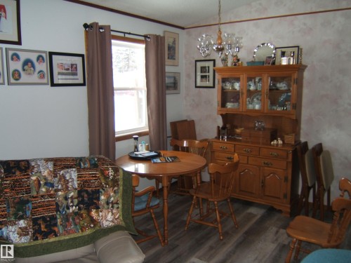 Inviting room featuring durable flooring, a window providing natural light, and a wooden hutch with glass-fronted display cabinets - 4702 52 Avenue, Two Hills, AB - Indoor Photo Showing Dining Room