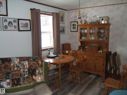 Inviting room featuring durable flooring, a window providing natural light, and a wooden hutch with glass-fronted display cabinets - 