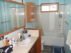 Bathroom featuring a white bathtub, a window with a wood frame, and a vanity with an integrated sink and mirror - 