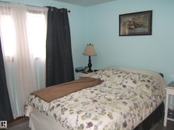 The room features light blue walls and a window with sheer white and dark curtains - 