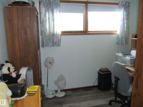 This room features two windows with roller blinds and patterned curtains - 4702 52 Avenue, Two Hills, AB - Indoor Photo Showing Office