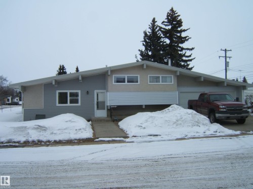 The property features a split-level design with a light-colored stucco and siding exterior - 4702 52 Avenue, Two Hills, AB - Outdoor With Facade