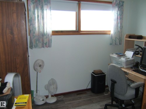 The room features two windows with roller blinds, and wood trim - 4702 52 Avenue, Two Hills, AB - Indoor Photo Showing Office