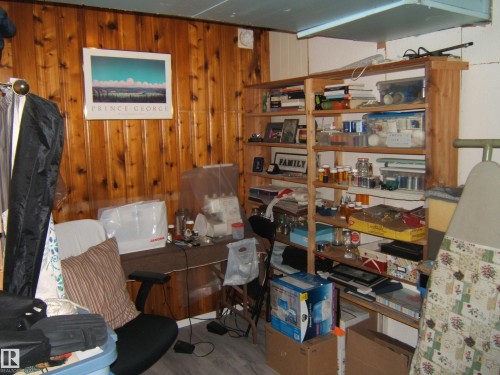 This room features wood paneling on one wall and a built-in wooden shelving unit - 4702 52 Avenue, Two Hills, AB - Indoor