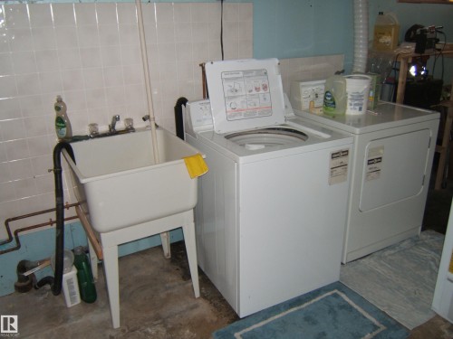 The property features a dedicated laundry area with a utility sink, washing machine, and dryer - 4702 52 Avenue, Two Hills, AB - Indoor Photo Showing Laundry Room
