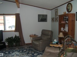 Living space featuring a vaulted ceiling with exposed beam, window with wood trim, and a patterned area rug - 