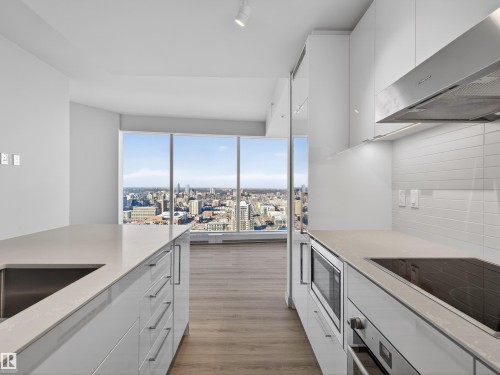 The kitchen features white cabinetry, integrated appliances, and a stainless steel sink, complemented by light-coloured countertops - 2612 10360 102 Street, Edmonton, AB - Indoor Photo Showing Kitchen