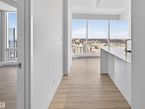 The property features expansive windows offering city views, light-toned flooring, and a modern kitchen island with a sink and faucet - 2612 10360 102 Street, Edmonton, AB - Indoor Photo Showing Other Room
