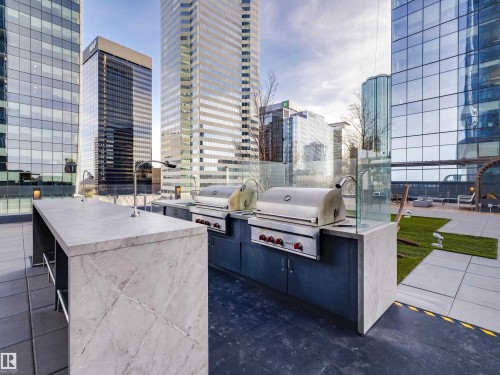 The rooftop terrace offers an outdoor kitchen with two built-in grills, a large island with a sink, and expansive views of the city skyline - 2612 10360 102 Street, Edmonton, AB - Outdoor With Deck Patio Veranda