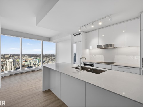 Modern kitchen featuring sleek white cabinetry, a large centre island with an undermount sink. - 2612 10360 102 Street, Edmonton, AB - Indoor Photo Showing Kitchen With Double Sink With Upgraded Kitchen
