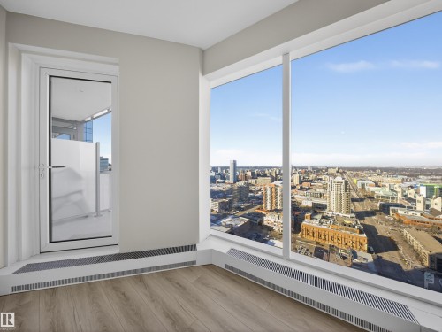 This living area features large windows offering extensive city views, light wood-style flooring, and a glass door leading to an outdoor space - 2612 10360 102 Street, Edmonton, AB - Indoor Photo Showing Other Room