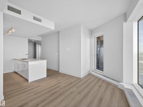 Modern kitchen island with a built-in sink, stainless steel faucet, and glossy white cabinetry - 2612 10360 102 Street, Edmonton, AB - Indoor