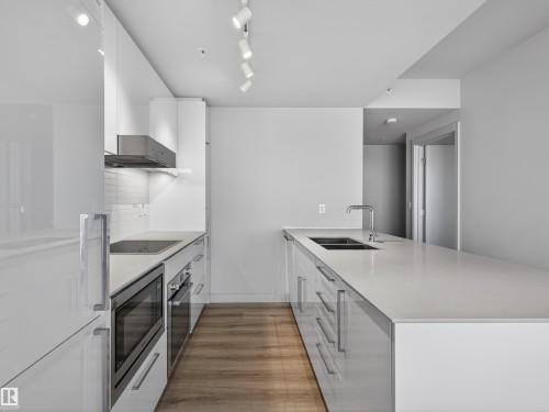 Contemporary kitchen featuring white cabinetry, light-coloured countertops, and stainless steel appliances - 2612 10360 102 Street, Edmonton, AB - Indoor Photo Showing Kitchen With Double Sink With Upgraded Kitchen