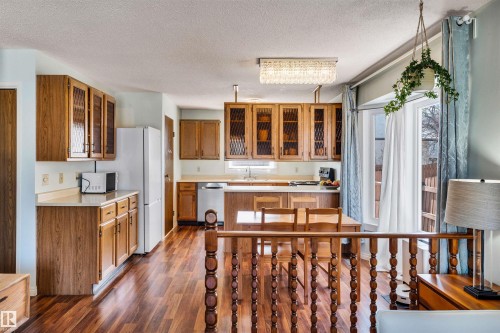 Well-appointed kitchen featuring wood cabinetry, white appliances, and a dining area with a built-in table - 18923 86A Avenue, Edmonton, AB - Indoor