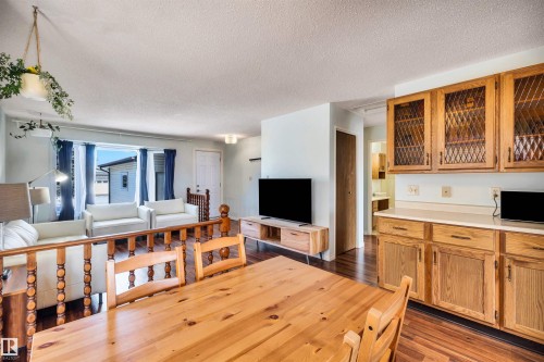 The dining area features a wooden table and chairs, with wood flooring extending throughout - 18923 86A Avenue, Edmonton, AB - Indoor