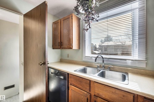 The kitchen features a double stainless steel sink with a chrome faucet, light-colored countertops, and wood cabinetry - 18923 86A Avenue, Edmonton, AB - Indoor Photo Showing Kitchen With Double Sink