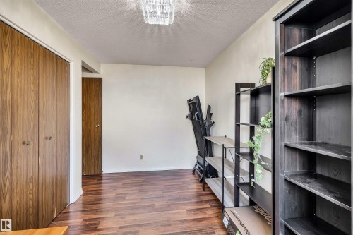 This versatile room features warm-toned wood-look flooring and a bright ceiling light fixture - 18923 86A Avenue, Edmonton, AB - Indoor Photo Showing Other Room