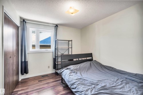 This room features wood-look flooring, a window with natural light, and a closet with bifold doors - 18923 86A Avenue, Edmonton, AB - Indoor Photo Showing Bedroom