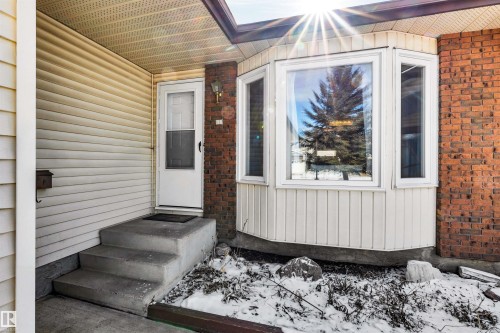 The property features a white exterior door with a storm door, concrete steps, and a bay window - 18923 86A Avenue, Edmonton, AB - Outdoor With Exterior