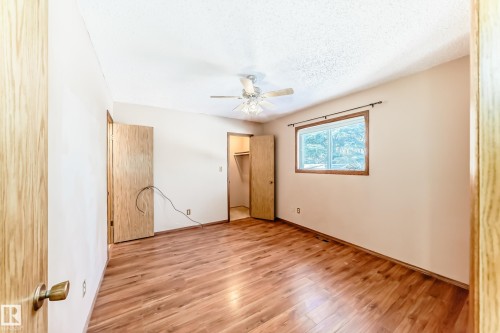 The room features wood flooring, a window with a wood trim, a ceiling fan, and two wooden doors - 100 23016 Twp Rd 504, Rural Leduc County, AB - Indoor Photo Showing Other Room