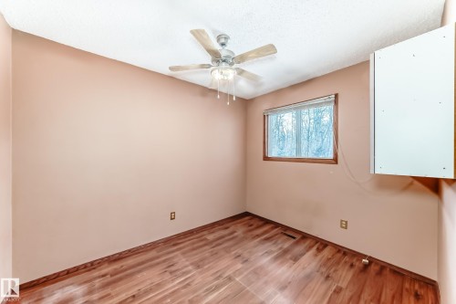 This room features hardwood flooring, a ceiling fan, and a window with a wooded view - 100 23016 Twp Rd 504, Rural Leduc County, AB - Indoor Photo Showing Other Room