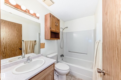 The bathroom features a vanity with an integrated sink, a large mirror, a shower-tub combination, and a toilet - 100 23016 Twp Rd 504, Rural Leduc County, AB - Indoor Photo Showing Bathroom
