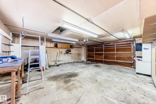 The property features a garage with a wooden garage door, overhead lighting, and built-in shelving - 100 23016 Twp Rd 504, Rural Leduc County, AB - Indoor Photo Showing Garage