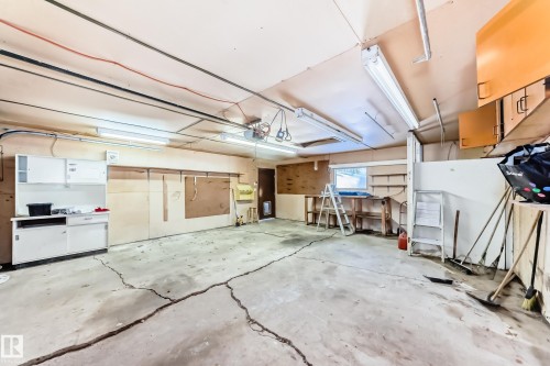 The property includes a spacious garage with a concrete floor, equipped with overhead fluorescent lighting and wall-mounted storage cabinets - 100 23016 Twp Rd 504, Rural Leduc County, AB - Indoor Photo Showing Garage