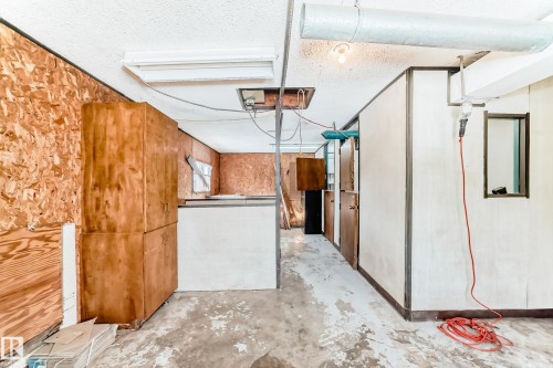 The property features exposed ceiling ductwork, a fluorescent light fixture, and an unfinished floor - 100 23016 Twp Rd 504, Rural Leduc County, AB - Indoor Photo Showing Other Room