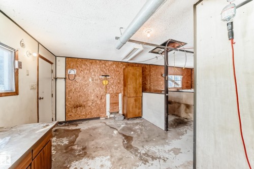 The property features a utility room with exposed plywood walls, a window, and a door - 100 23016 Twp Rd 504, Rural Leduc County, AB - Indoor