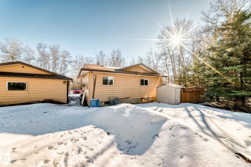 The property features a building with light brown siding and a brown roof, with a smaller shed visible - 100 23016 Twp Rd 504, Rural Leduc County, AB - Outdoor
