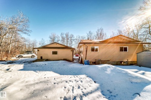 The property features a main dwelling and a detached outbuilding, both with light-colored siding and brown roofs - 100 23016 Twp Rd 504, Rural Leduc County, AB - Outdoor