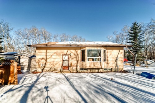 The property features a light-colored exterior with a bay window and a brown roof - 100 23016 Twp Rd 504, Rural Leduc County, AB - Outdoor
