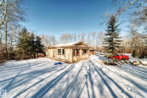 The property features a wood-sided exterior and a sloped roof - 100 23016 Twp Rd 504, Rural Leduc County, AB - Outdoor