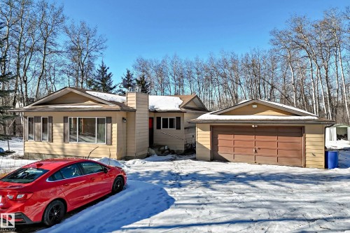 The property features a ranch-style house with an attached garage, a covered front entrance, and a front sunroom with large windows - 100 23016 Twp Rd 504, Rural Leduc County, AB - Outdoor