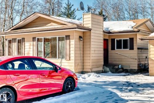 The property features a light-colored exterior with a brown roof and matching window shutters - 100 23016 Twp Rd 504, Rural Leduc County, AB - Outdoor